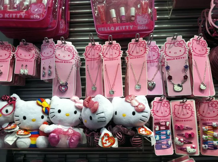 Hello Kitty temalı pelüş oyuncaklar, kolyeler ve aksesuarların sergilendiği renkli vitrin görünümü.